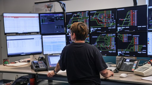 Eine Zugverkehrssteuerin blickt im elektronischen Stellwerk der Bahn auf Monitore