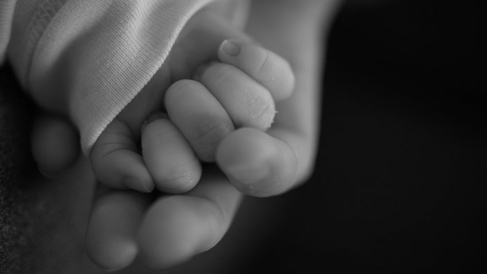 Eine Hand hält eine kleine Babyhand
