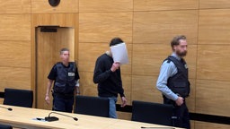 Philippos im Gerichtssaal mit zwei Wachmeistern 