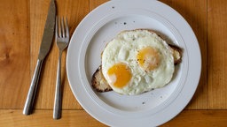 Zwei Spiegeleier und eine Scheibe Brot sind auf einem Teller serviert