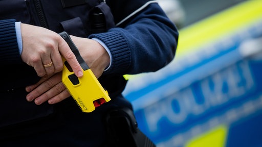 Ein Polizist hält einen Taser