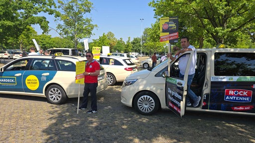 Taxifahrer-Protest in Düsseldorf mit Taxis und Protestschildern auf einem Parkplatz