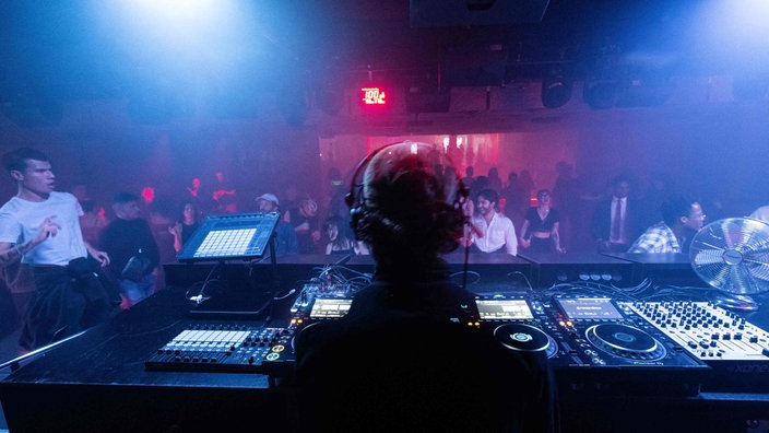 Ein DJ legt Techno Musik in einem Nachtclub auf