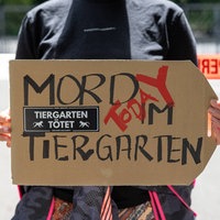Eine Demonstrierende hält ein handbeschriftetes Pappschild mit der Aufschrift Mord im Tiergarten