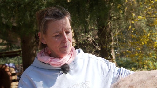 Eine verzweifelt ausschauende Frau guckt von der Kamera weg