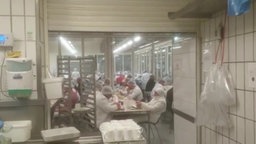Mehrere Arbeiter sitzen eng beieinander in der Kantine des Fleischherstellers Tönnies.
