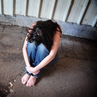 Junge Frau kauert ängstlich auf dem Boden