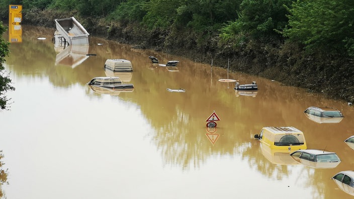 Auf einer bei den Unwettern überfluteten Straße sind nur noch die Dächer der Autos im Wasser zu erkennen