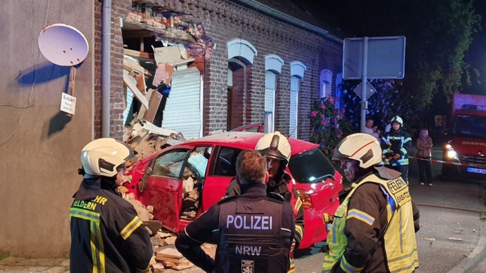 Ein roter Kleinwagen hat mit der Front eine Backsteinfassade durchbrochen