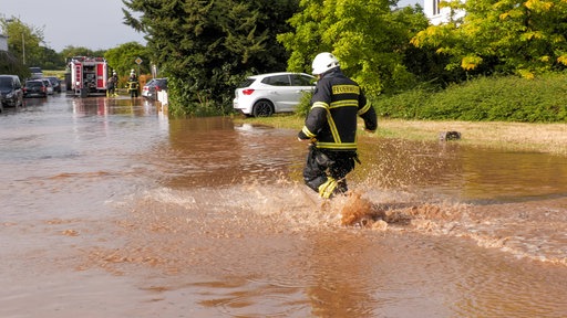 Ein Feuerwehrmann läuft durch Hochwasser 