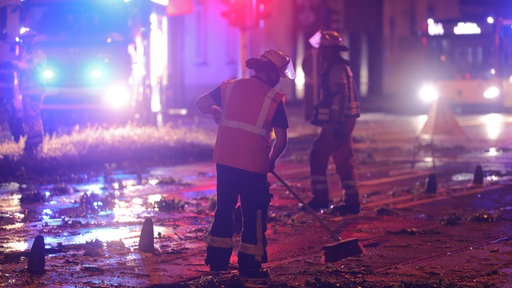 Feuerwehrleute fegen Blätter und Äste von den Schienen
