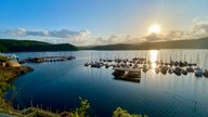 Ein kleiner Bootsanlegesteg am Schwammenaul Rursee in der Eifel mit sinkender Sonne