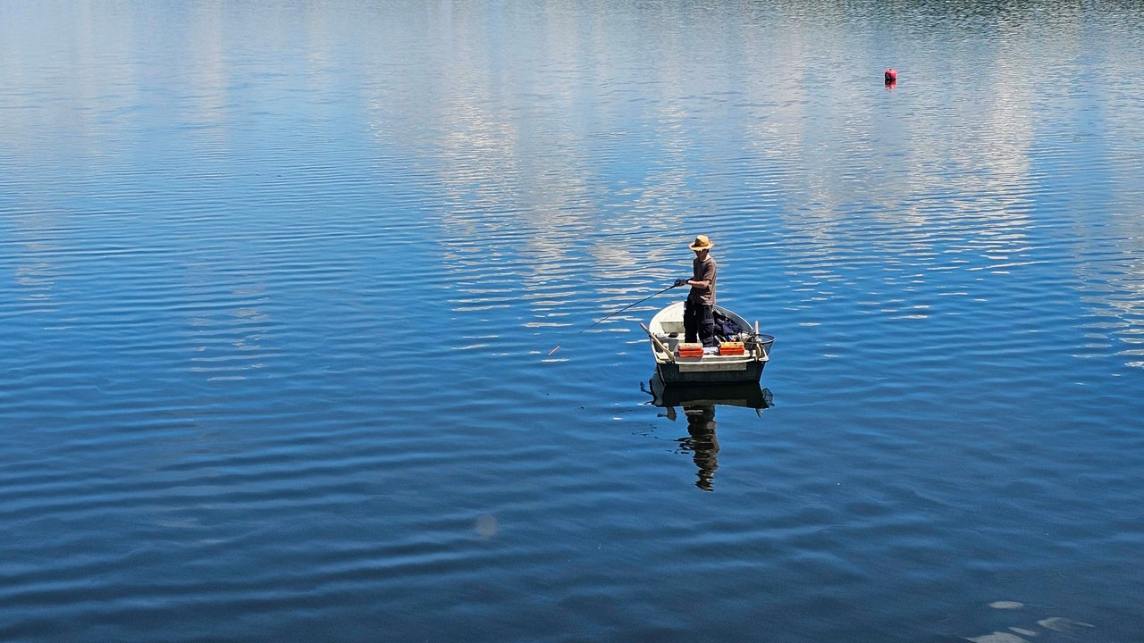 Ein Angler auf einem Boot auf der Möhnetalsperre