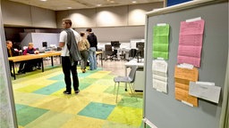 Drei Personen stehen in einem Wahllokal in Bonn.