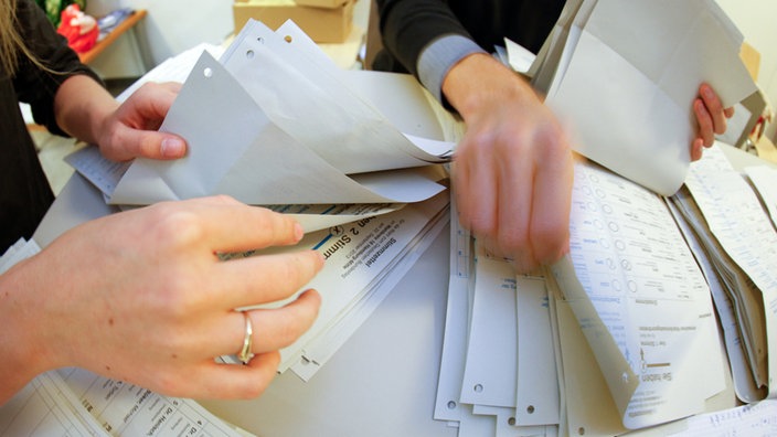 Wahlhelfer zählen Stimmzettel aus. 