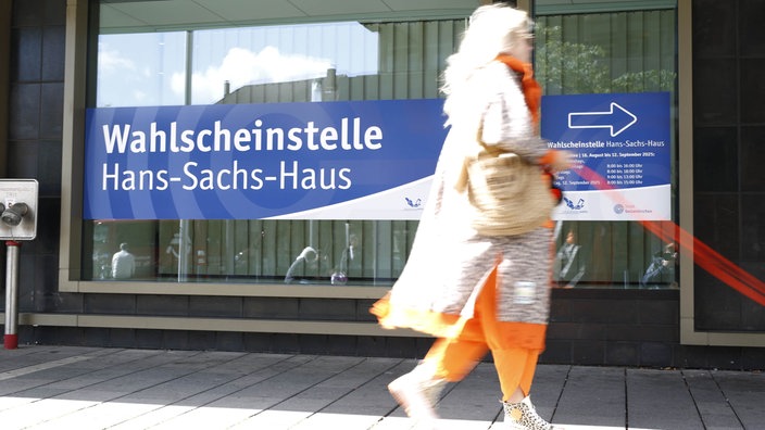 Eine Frau läuft an der Wahlscheinstelle Hans-Sachs-Haus vorbei 