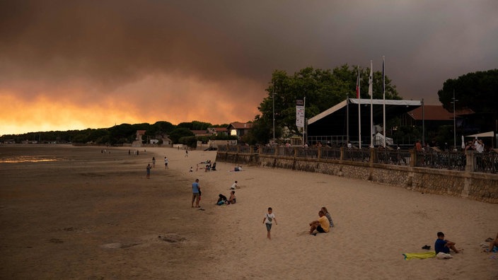 Frankreich, in der Nähe von Bordeaux: Menschen am Strand Andernos-Les-Bains während eines Waldbrands nachdem ein Teil der umliegenden Gegend evakuiert wurde