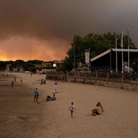 Frankreich, in der Nähe von Bordeaux: Menschen am Strand Andernos-Les-Bains während eines Waldbrands nachdem ein Teil der umliegenden Gegend evakuiert wurde