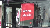 Auf einer Busscheibe hängt ein Plakat von Verdi mit der Aufschrift "Heute: Warnstreik!"