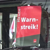 Auf einer Busscheibe hängt ein Plakat von Verdi mit der Aufschrift "Heute: Warnstreik!"