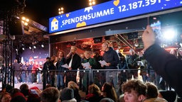 Die Moderatoren verbeugen sich vor der Menge mit Glitzer-Fontänen