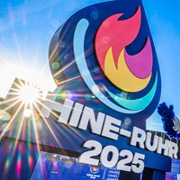 Die tiefstehende Sonne scheint durch das überdimensionale Logo der Welthochschulspiele