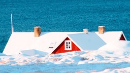 Das Dach eines roten Hauses ist über einem Eisberg zu sehen