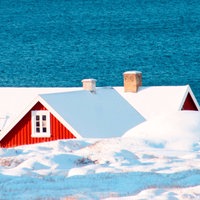 Das Dach eines roten Hauses ist über einem Eisberg zu sehen
