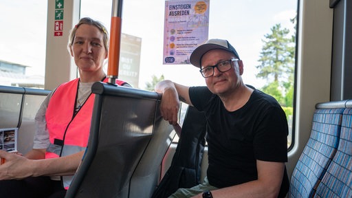 Eine Organisatorin und ein Teilnehmer der Begegnungsbahn sitzen in einer Stadtbahn