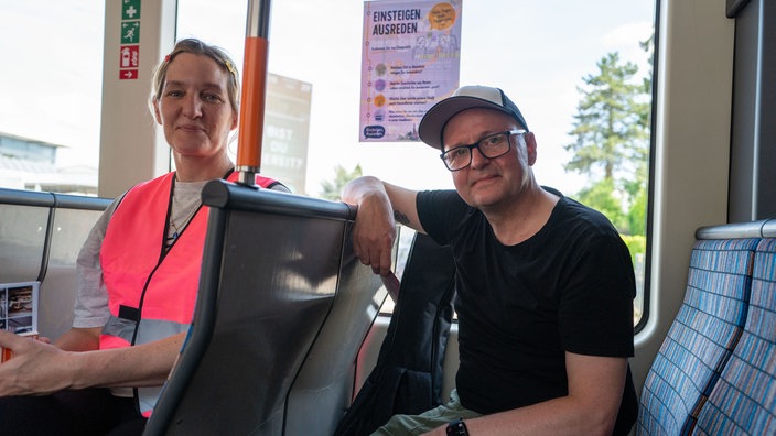 Eine Organisatorin und ein Teilnehmer der Begegnungsbahn sitzen in einer Stadtbahn