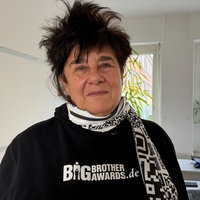Jurymitglied Rena Tangens steht in einem Büro und trägt einen schwarzen Pullover der Big Brother Awards.