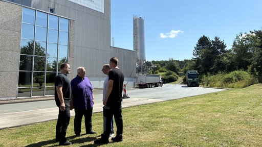 Gewerkschaftsmitglieder stehen im Kreis vor Brauerei