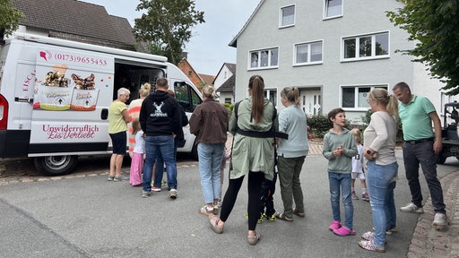 Kinder und Erwachsende stehen vor dem Eiswagen