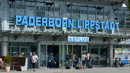 In das Abflugterminal des Flughafens Paderborn/Lippstadt gehen mehrere Reisende.