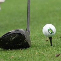 Ein Schläger vor einem Golfball, der auf einem Tee liegt.