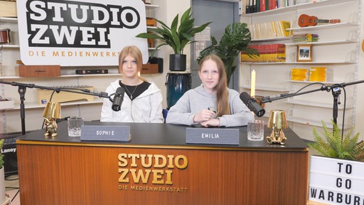 Sophie und Emilia sitzen am "Studio Zwei" Moderationspult