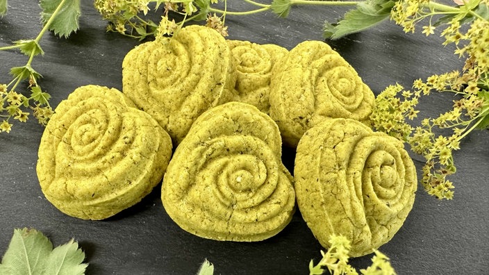 Gelbliche Kekse in Herzform und mit Rosenmuster. 