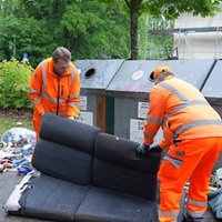 Zwei Männer der Stadtreinigung verladen ein Sofa.