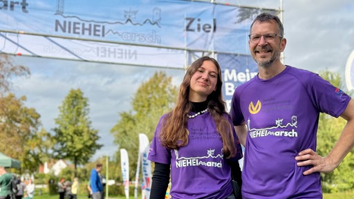 Sophia Florin steht gemeinsam mit ihrem Vater vor einem Banner des NIEHEIMarschs.