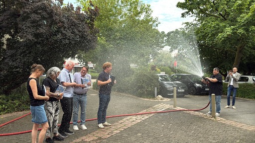 Mehrere Politikerinnen und Politiker werden als Protestaktion nass gespritzt.