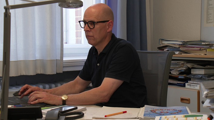 Joachim Held sitzt an einem Schreibtisch.
