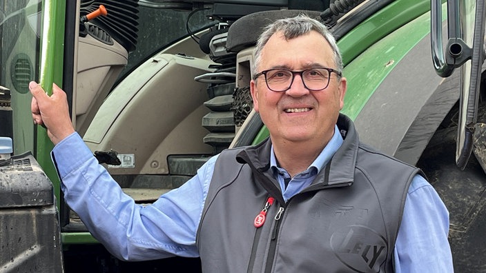 Antonius Tillmann schaut in die Kamera vor einem Traktor