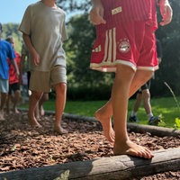 Kinder laufen über den Barfußpfad mit Rindenmulch.