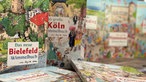 Nahaufnahme mehrerer Wimmelbücher; scharf im Vordergrund die Ausgaben aus Bielefeld und Köln, die übrigen stehen unscharf dahinter.