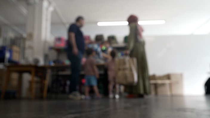 Eine Familie ist unscharf vor einigen Schulranzen zu sehen, die sie sich gerade ansieht.