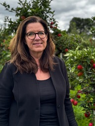 Frau steht vor Obstbäumen