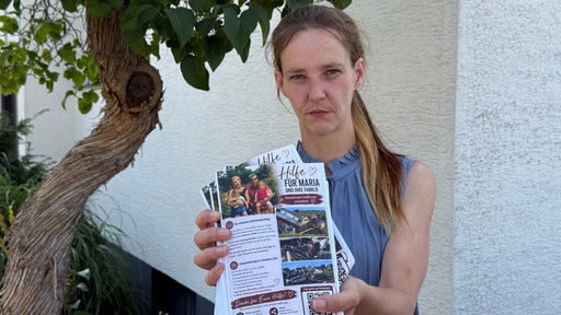 Eine Frau, Ramona Bosse, hält Flyer in der Hand.