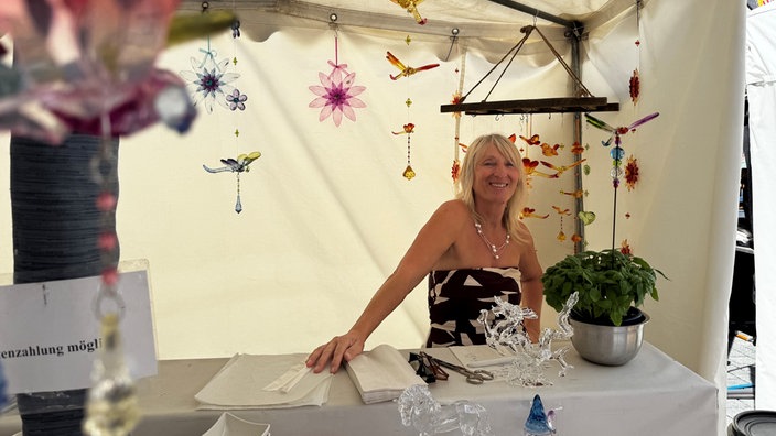 Schaustellerin auf dem Volksfest, hinter ihr bunte Deko Anhänger