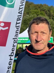 Ein Mann steht vor einer Fahne des Weserbergland-Triathlons.