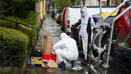 Beamte der Spurensicherung sichern nach einem Messerangriff Beweismittel auf einem Gehweg.